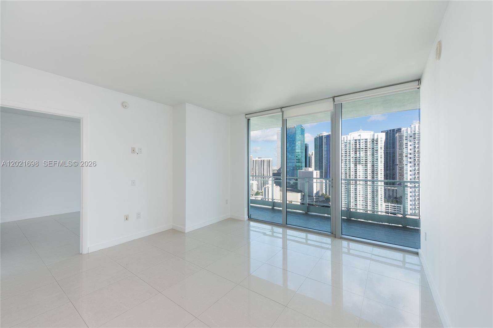 An empty room with white tile floors, white walls, and floor-to-ceiling windows overlooking a city — 92 SW 3rd Street # 2812, Miami FL 33130, MIAMI, FL