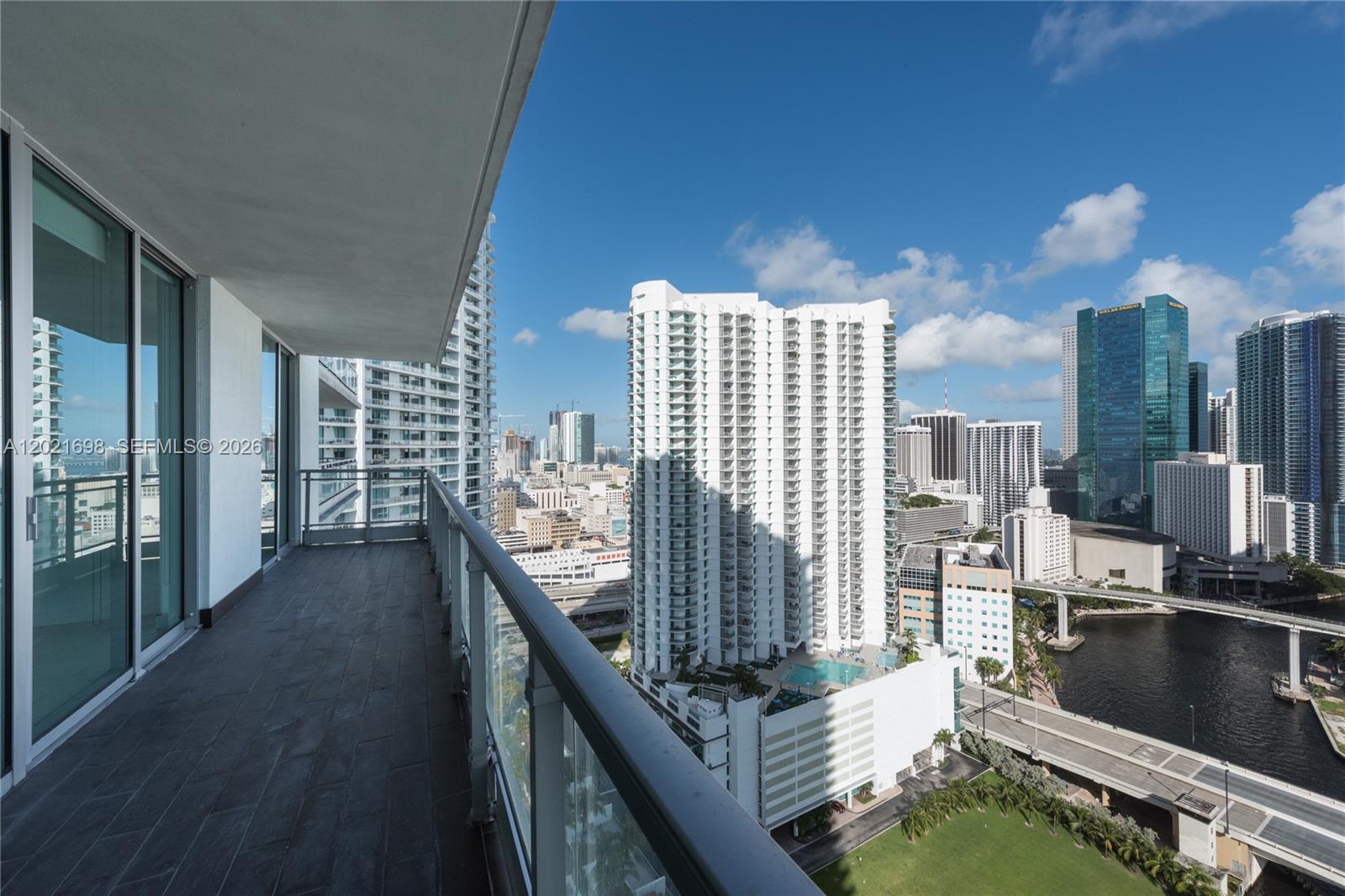 A balcony with dark tile flooring overlooks a dense city skyline and a river — 92 SW 3rd Street # 2812, Miami FL 33130, MIAMI, FL