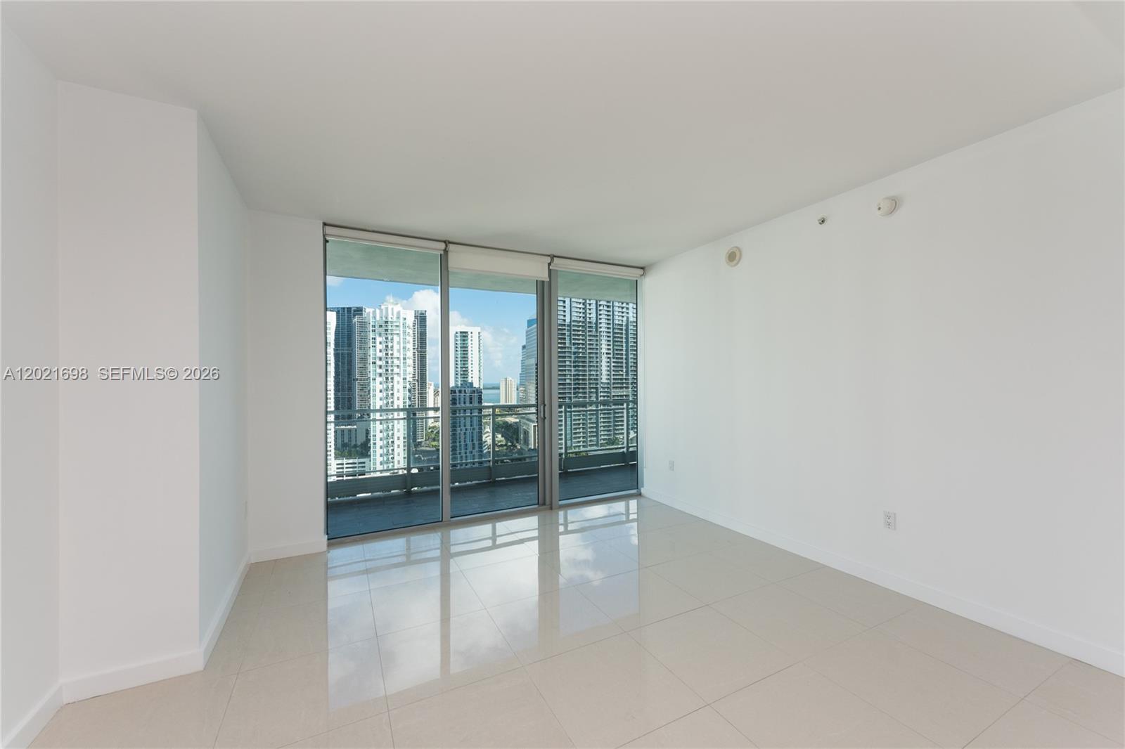 An empty room features white walls, light tile flooring, and floor-to-ceiling windows overlooking a city — 92 SW 3rd Street # 2812, Miami FL 33130, MIAMI, FL