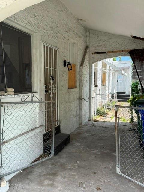 A concrete walkway leads to a doorway with a metal security gate and exterior lighting — 3322 SW 9th St, Miami FL 33135, MIAMI, FL