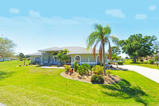 A single-story house with a light green exterior, arched windows, and a palm tree out front — 424 Holly Drive, Sebring FL 33876, SEBRING, FL