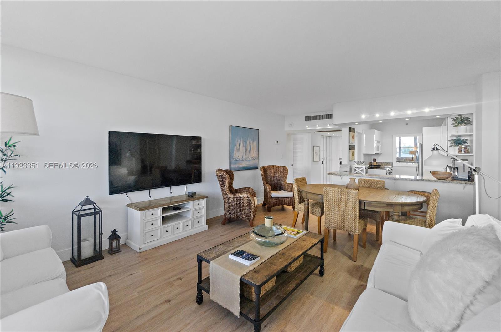 A living and dining area features white sofas, a wooden coffee table, and wicker chairs — 100 Lincoln Rd # 410, Miami Beach FL 33139, MIAMI BEACH, FL