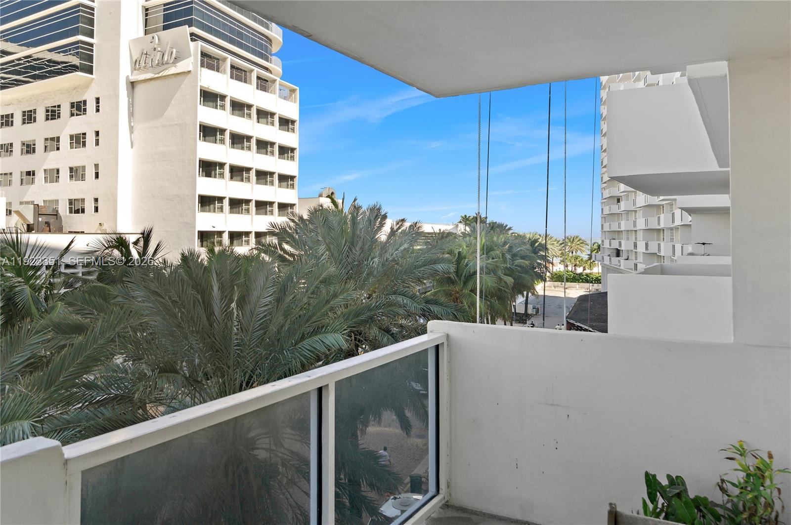 A balcony view overlooks palm trees, a parking area, and nearby high-rise buildings — 100 Lincoln Rd # 410, Miami Beach FL 33139, MIAMI BEACH, FL