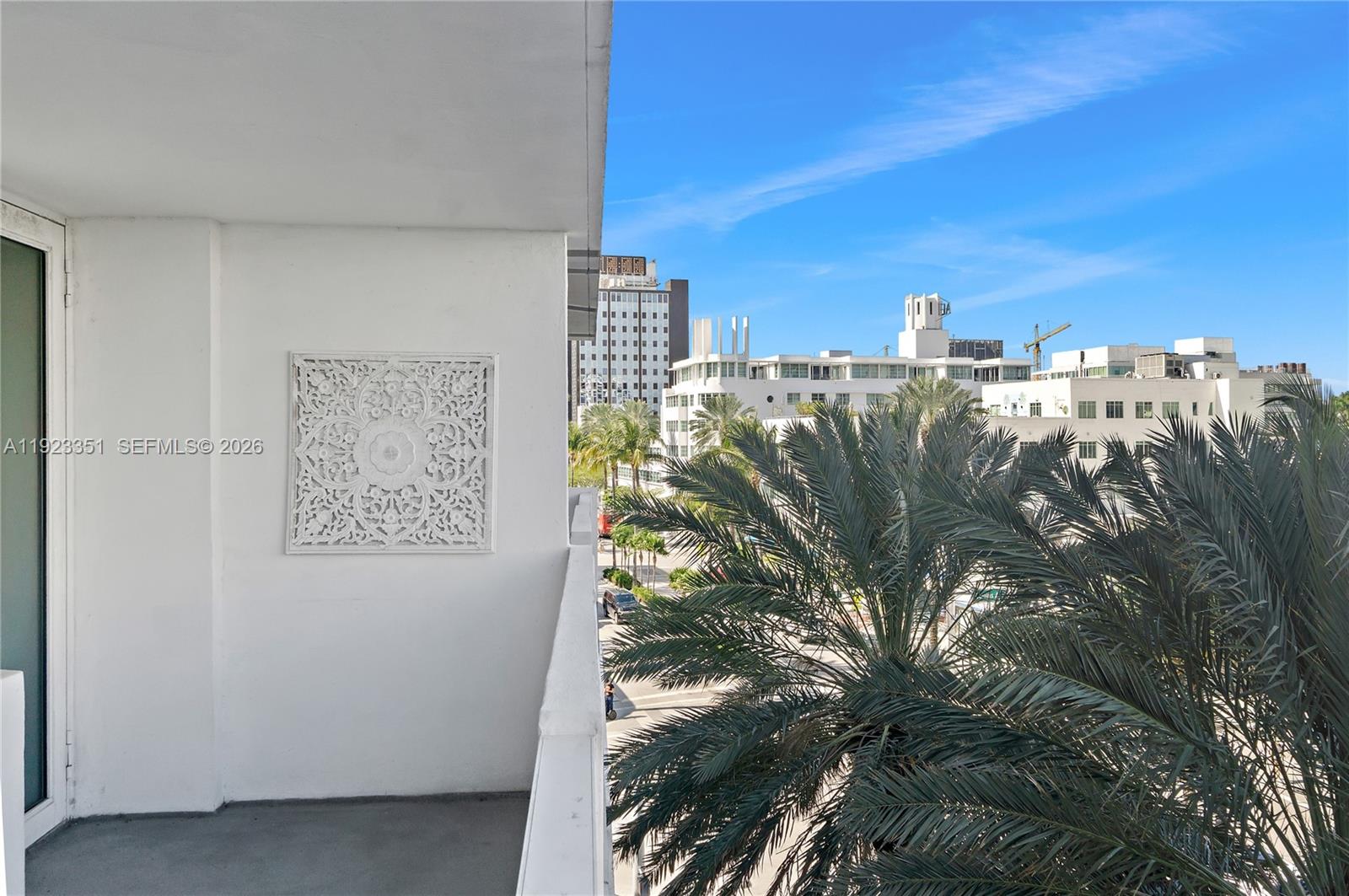 A balcony with a decorative white wall panel overlooks a street with palm trees — 100 Lincoln Rd # 410, Miami Beach FL 33139, MIAMI BEACH, FL