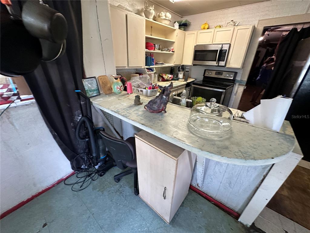 A kitchen features white cabinets, a stainless steel microwave, and a curved breakfast bar — 1105 NE 1ST STREET, MULBERRY, FL