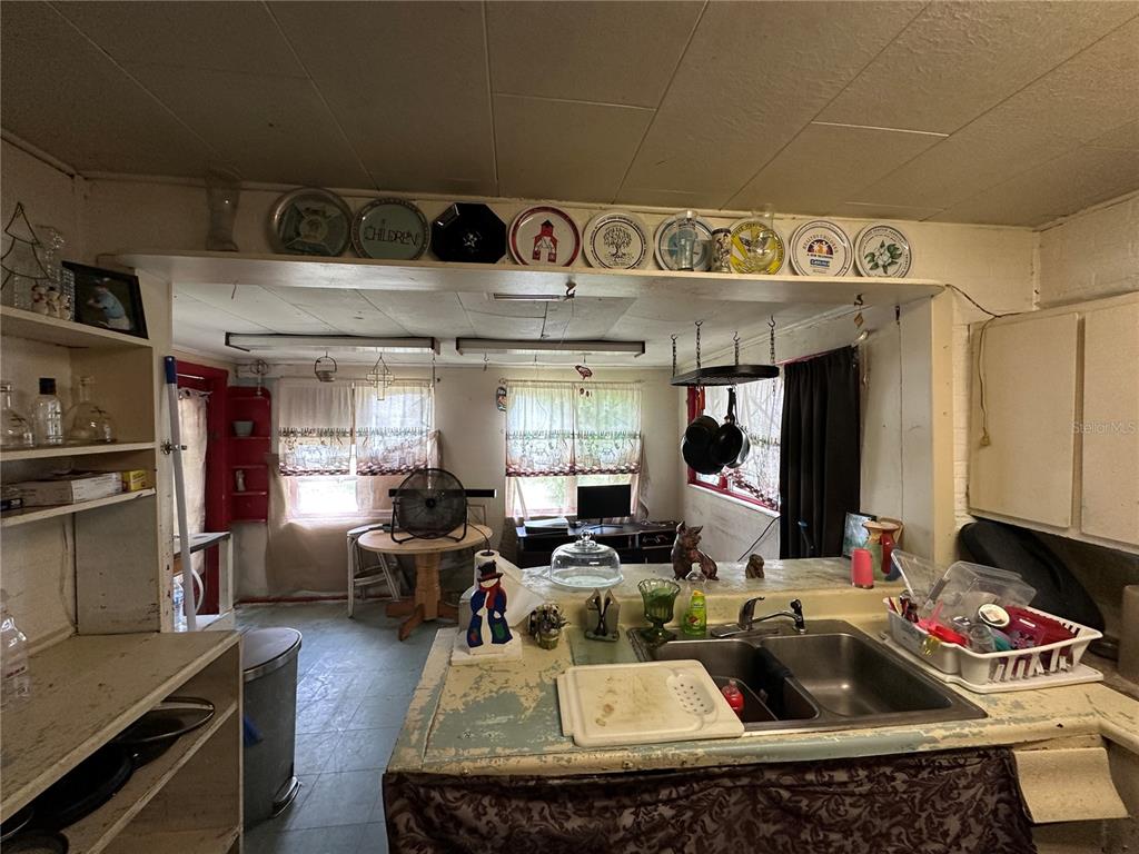 A kitchen with a double sink, open shelving, and a dining area with two windows — 1105 NE 1ST STREET, MULBERRY, FL