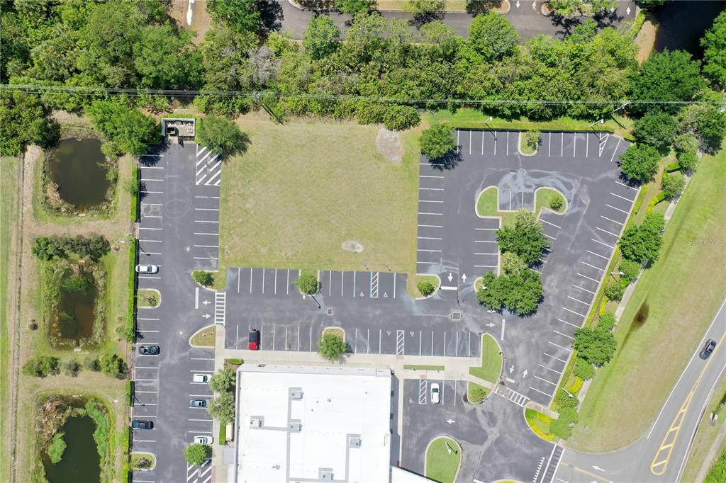 An aerial view shows a vacant lot surrounded by parking spaces and a commercial building — 7965 SPYGLASS HILL ROAD, VIERA, FL