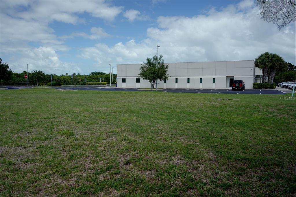 A large grassy field sits in front of a commercial building with a parking lot — 7965 SPYGLASS HILL ROAD, VIERA, FL