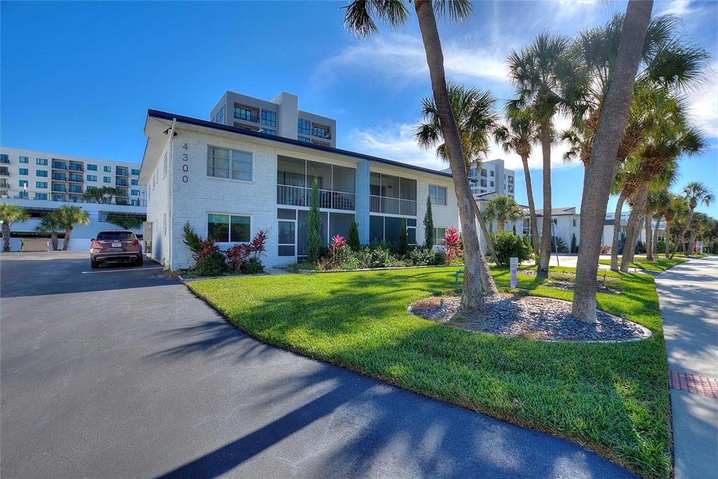A two-story white building with screened balconies sits next to a parking lot and lawn — 4300 37TH STREET S UNIT 4, ST PETERSBURG, FL