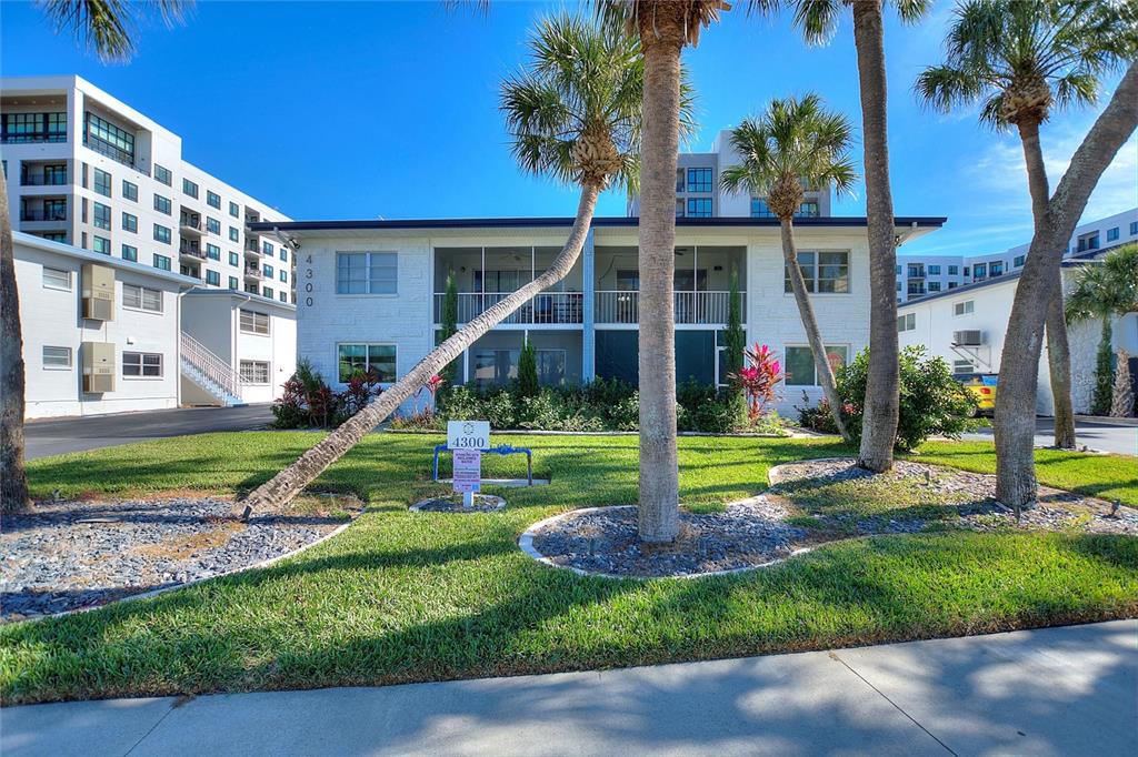 A two-story white apartment building features screened balconies, palm trees, and a grassy lawn — 4300 37TH STREET S UNIT 4, ST PETERSBURG, FL
