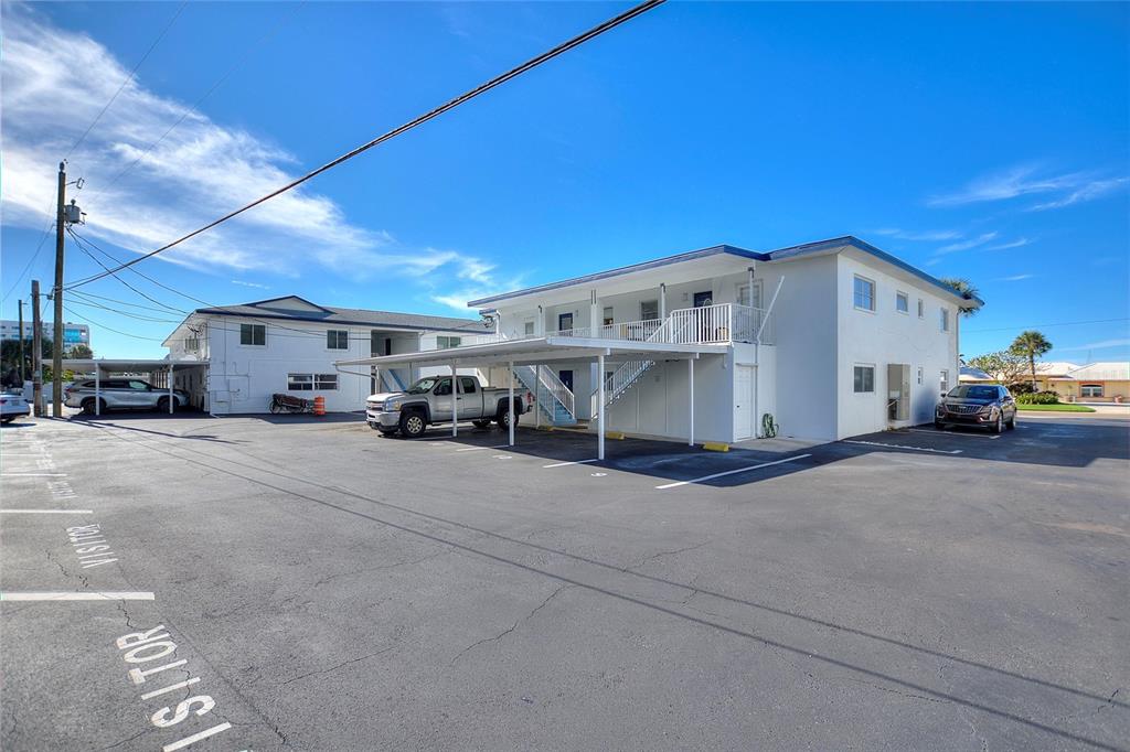 Two white two-story apartment buildings with covered parking spaces sit on an asphalt lot — 4300 37TH STREET S UNIT 4, ST PETERSBURG, FL