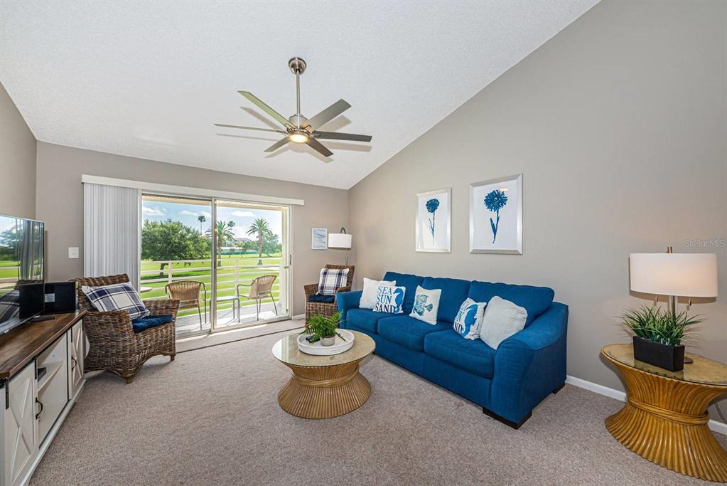 A living room features a blue sofa, wicker chairs, a coffee table, and a sliding door — 6077 BAHIA DEL MAR BOULEVARD UNIT 221, ST PETERSBURG, FL