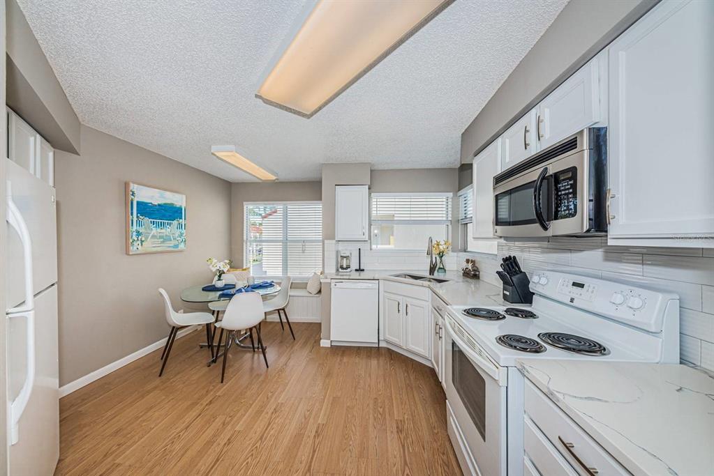 A kitchen with white cabinets, stainless steel appliances, and an adjacent dining area with seating — 6077 BAHIA DEL MAR BOULEVARD UNIT 221, ST PETERSBURG, FL
