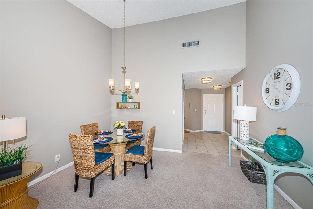 A dining area features a glass-topped table, wicker chairs, a chandelier, and a console table — 6077 BAHIA DEL MAR BOULEVARD UNIT 221, ST PETERSBURG, FL