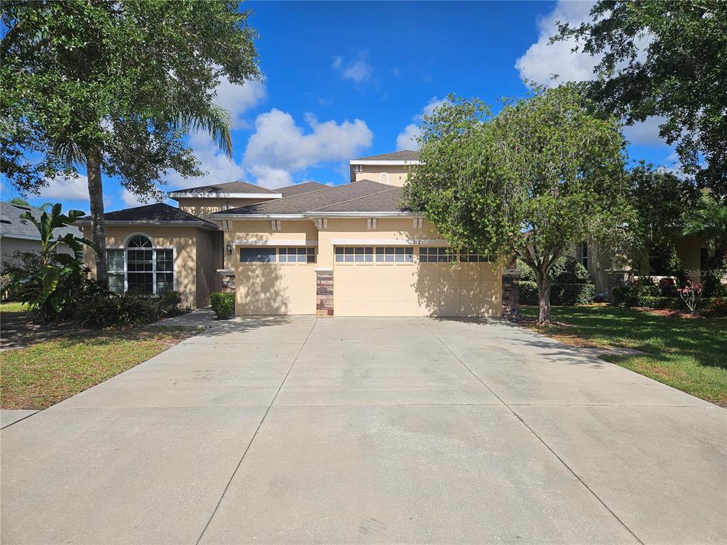 A tan single-story house with a three-car garage and a concrete driveway — 118 PEONY COURT, BRADENTON, FL