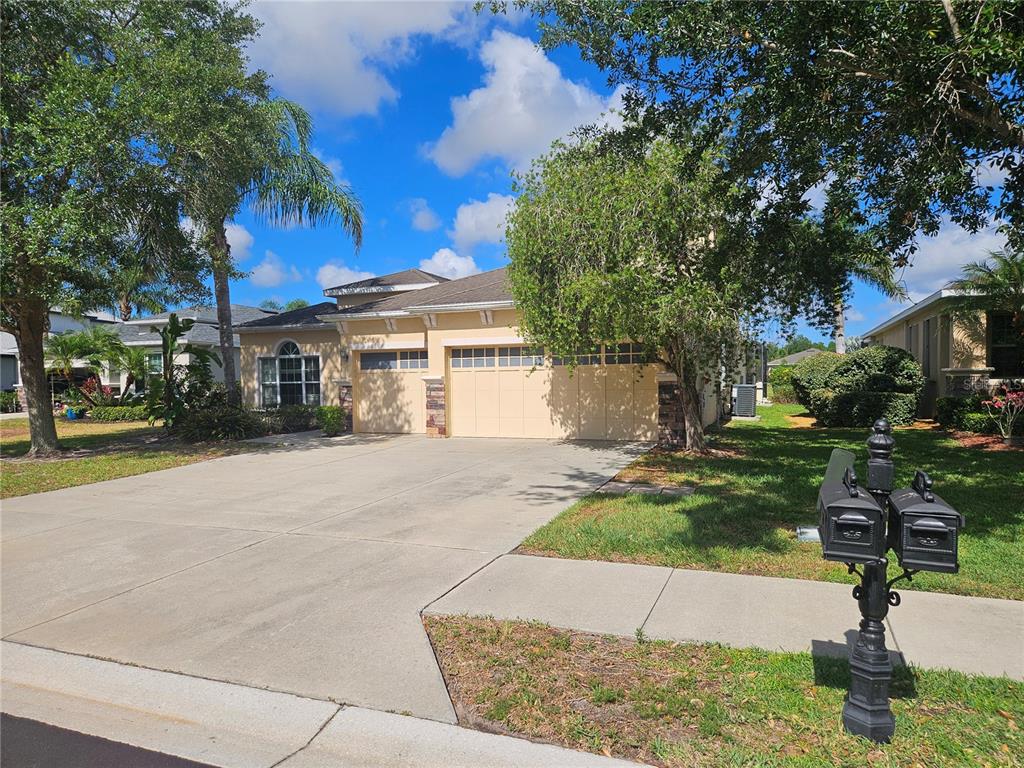 A tan single-story house with a three-car garage and a concrete driveway — 118 PEONY COURT, BRADENTON, FL