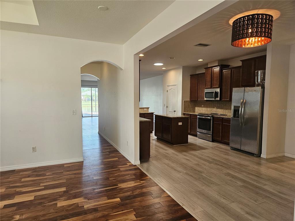 A kitchen with dark wood cabinets and stainless steel appliances sits beside a living area — 118 PEONY COURT, BRADENTON, FL