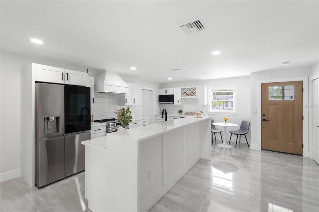 A modern kitchen features white cabinetry, a large waterfall island, and stainless steel appliances — 1715 DELAWARE AVENUE NE, ST PETERSBURG, FL