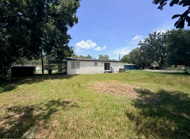 A white manufactured home sits on a grassy lot under a bright blue sky — 4394 RAMBLEWOOD N, MULBERRY, FL
