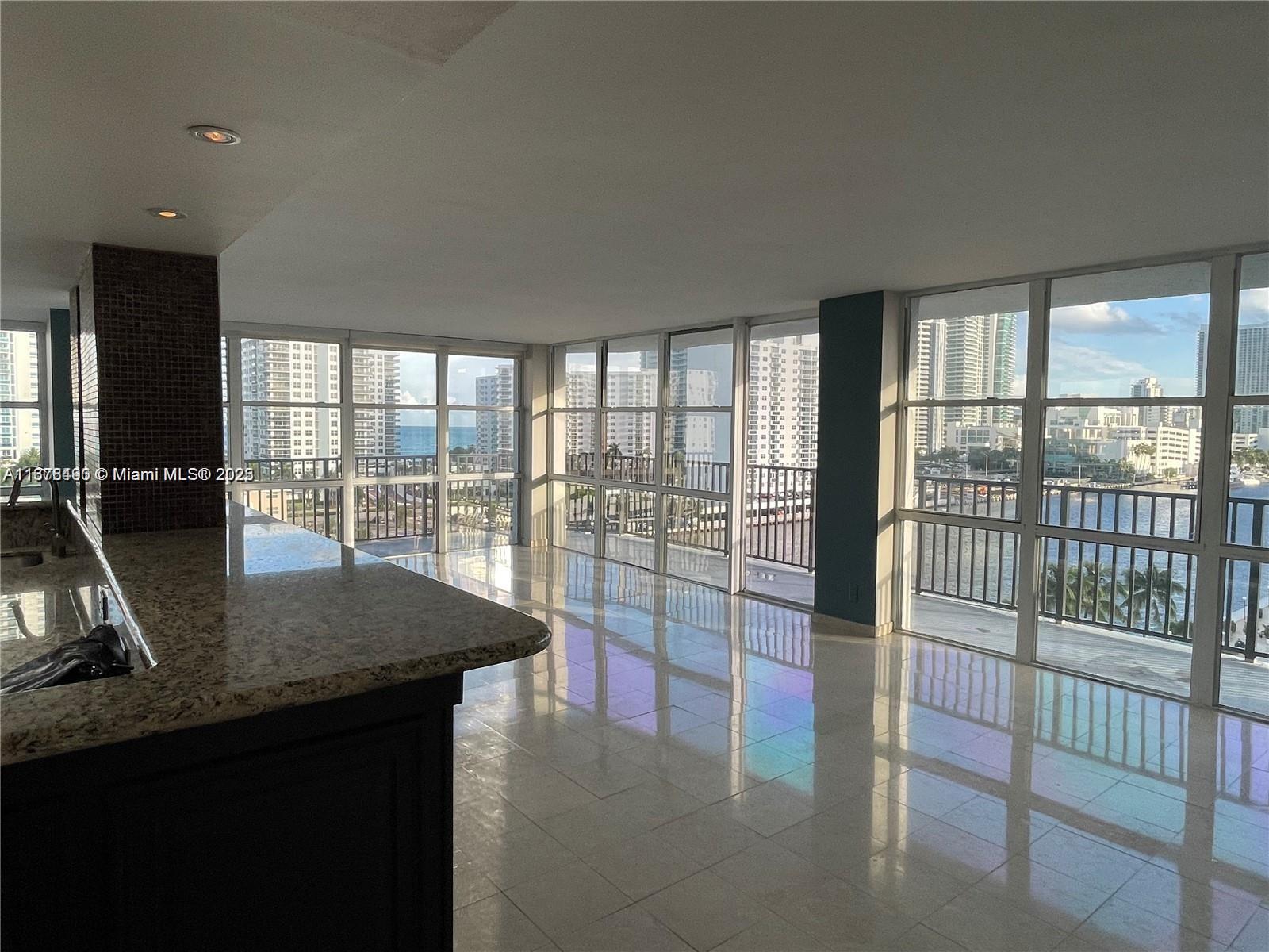 A kitchen with granite countertops overlooks a living area with floor-to-ceiling windows and water views — 1000 Parkview Dr # 920, Hallandale Beach FL 33009, HALLANDALE BEACH, FL