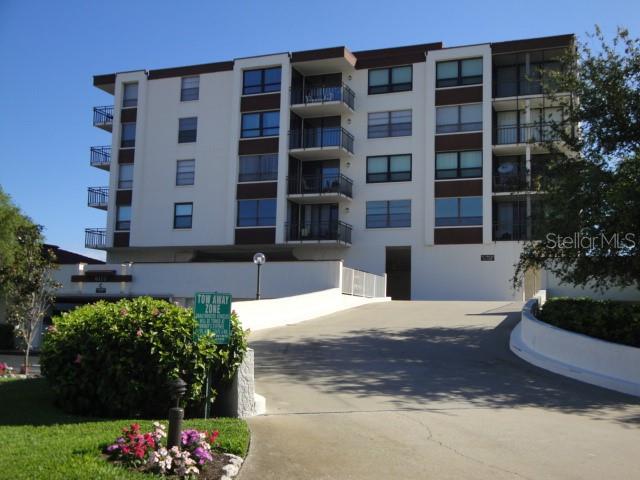 A multi-story apartment building with balconies and a concrete driveway leading to a parking area — 6177 SUN BOULEVARD UNIT 405, ST PETERSBURG, FL