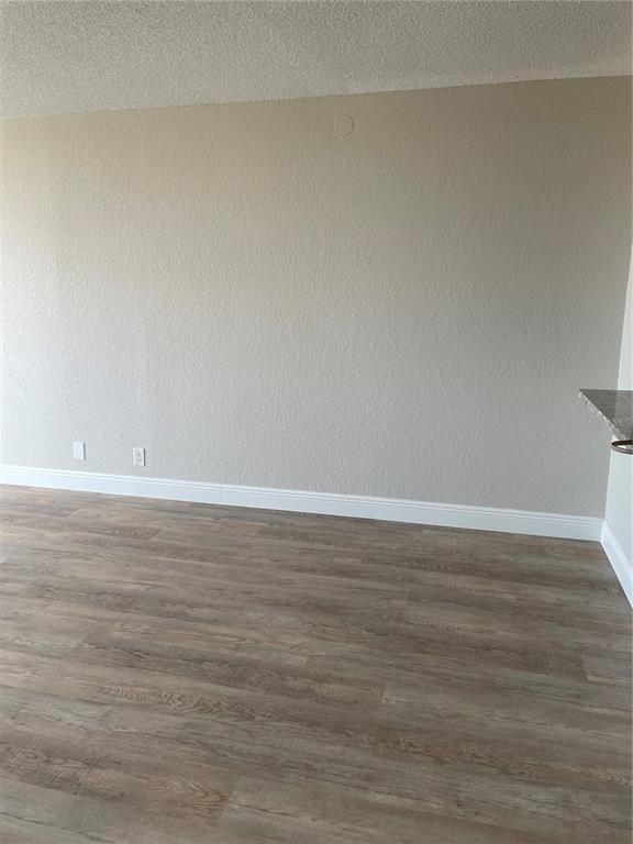 An empty room features light-colored walls, white baseboards, and wood-look laminate flooring — 6177 SUN BOULEVARD UNIT 405, ST PETERSBURG, FL
