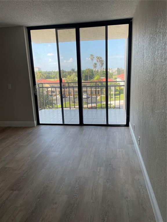 An empty room with light wood-look flooring and sliding glass doors leading to a balcony — 6177 SUN BOULEVARD UNIT 405, ST PETERSBURG, FL