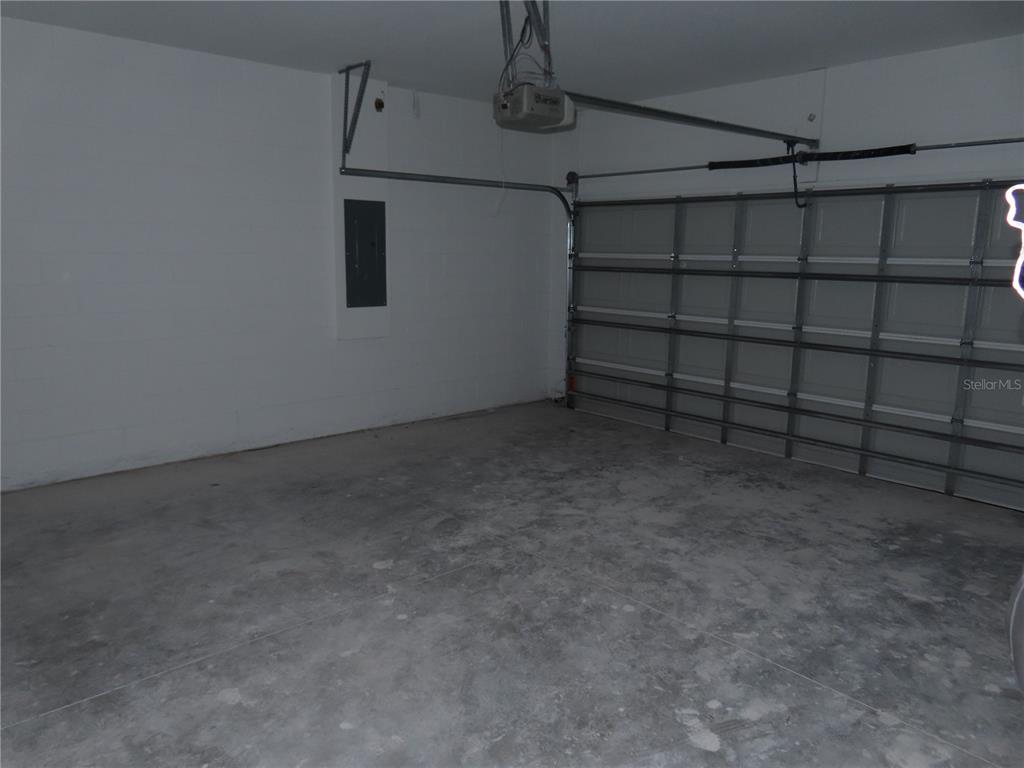 An empty garage with a concrete floor, a sectional door, and a wall-mounted electrical panel — 4525 RALEIGH STREET, ORLANDO, FL