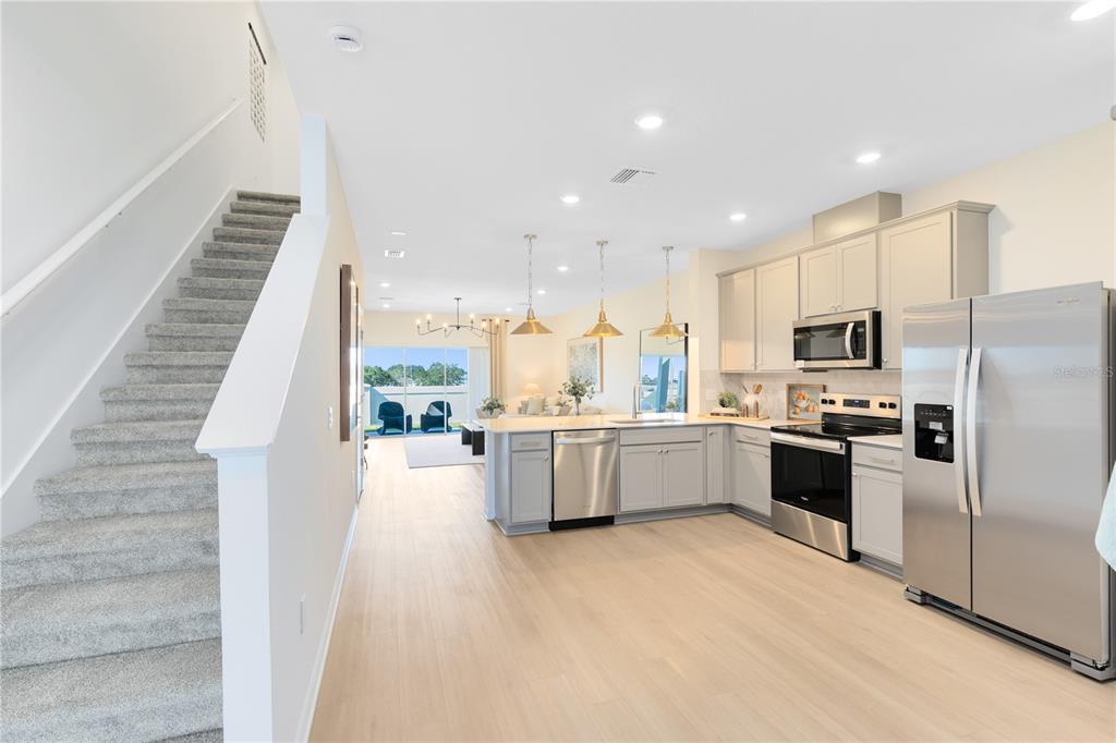 A kitchen with light gray cabinets and stainless steel appliances opens to a living area — 4340 CHESTER SPRINGS BOULEVARD, DAVENPORT, FL