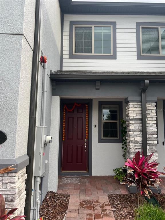 The exterior of a townhouse features a red front door, stone accents, and a walkway — 393 EVERTREE LOOP, SANFORD, FL