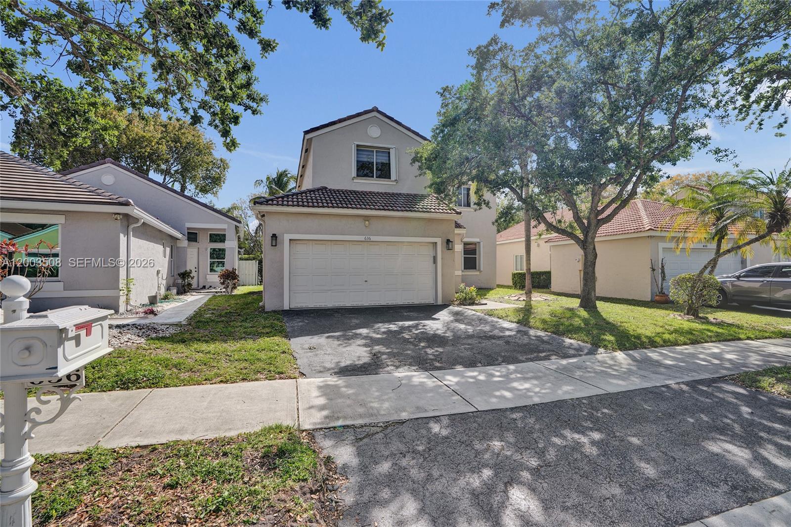 A two-story suburban house with a garage, driveway, and front yard under a blue sky — 636 Sand Creek Cir, Weston FL 33327, WESTON, FL