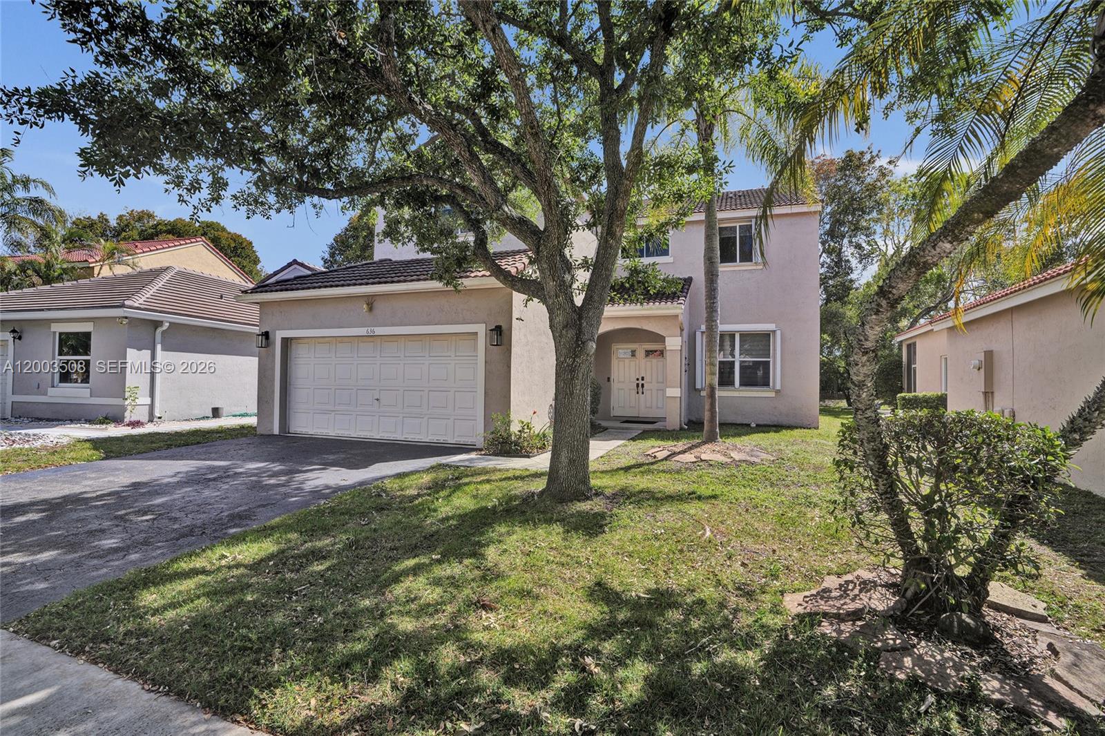 A two-story suburban house features a garage, a front entrance, and a large shade tree — 636 Sand Creek Cir, Weston FL 33327, WESTON, FL