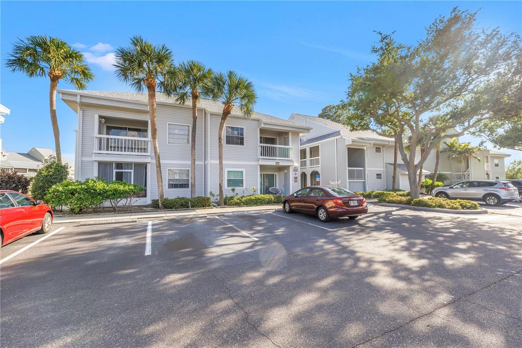 A two-story apartment building with light-colored siding stands behind a paved parking lot — 6939 STONES THROW CIRCLE N UNIT 6206, ST PETERSBURG, FL