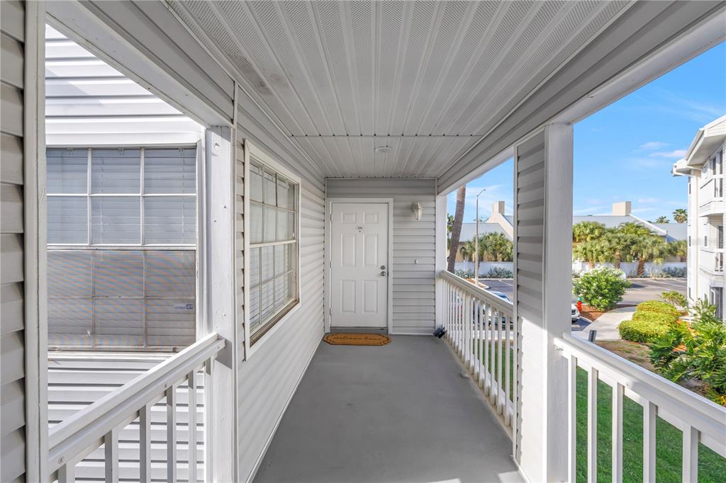 An exterior view of a covered apartment balcony with white railings and a front door — 6939 STONES THROW CIRCLE N UNIT 6206, ST PETERSBURG, FL