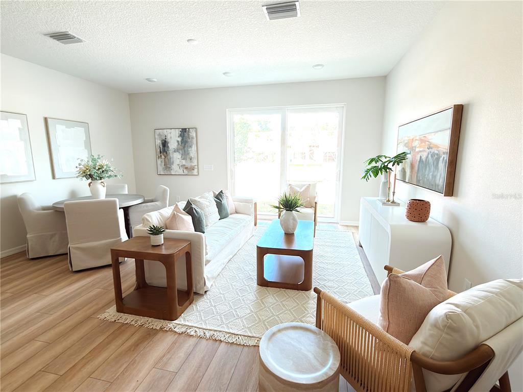 A modern kitchen with white cabinets and stainless steel appliances opens to a living area — 5837 ANGELA LEYLA PLACE, RIVERVIEW, FL