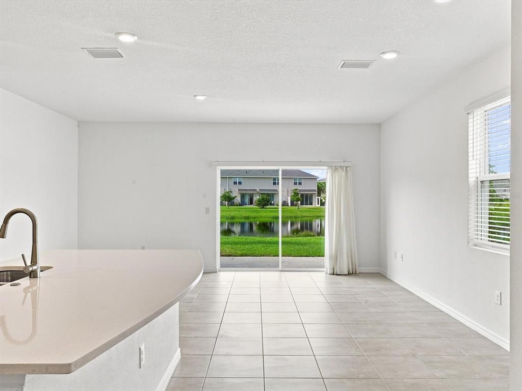 A bright kitchen and living area with tile floors, a breakfast bar, and sliding glass doors — 5739 ARCHIPELAGO STREET, NOKOMIS, FL