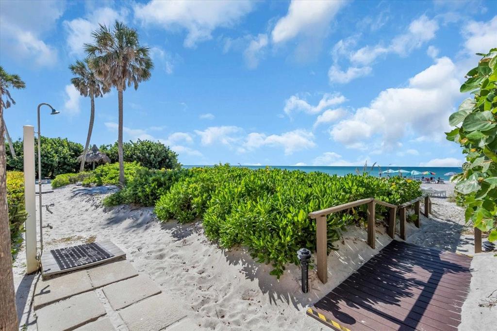 A sandy path with a wooden walkway leads through green shrubs toward the ocean — 5841 GULF OF MEXICO DRIVE UNIT 244, LONGBOAT KEY, FL