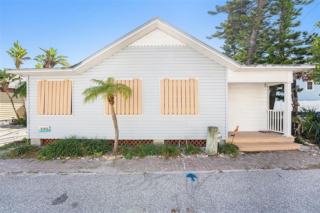 A light-colored, single-story house with boarded-up windows and a small front porch — 125 95TH AVENUE, TREASURE ISLAND, FL