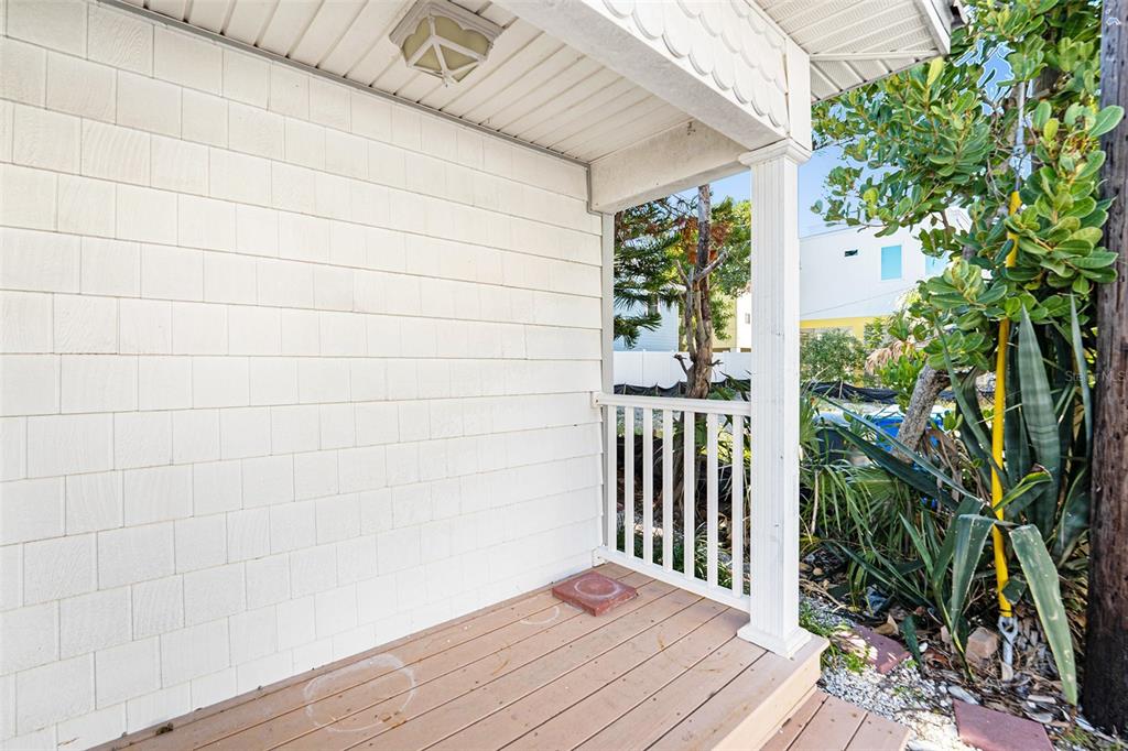 A covered wooden porch features white shingle siding, a white railing, and a support column — 125 95TH AVENUE, TREASURE ISLAND, FL