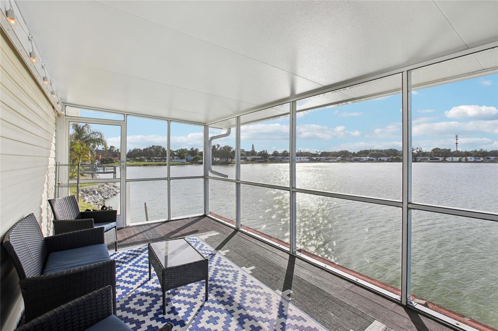 A screened-in porch features wicker furniture, a patterned rug, and expansive views of a lake — 8420 FANTASIA PARK WAY, RIVERVIEW, FL