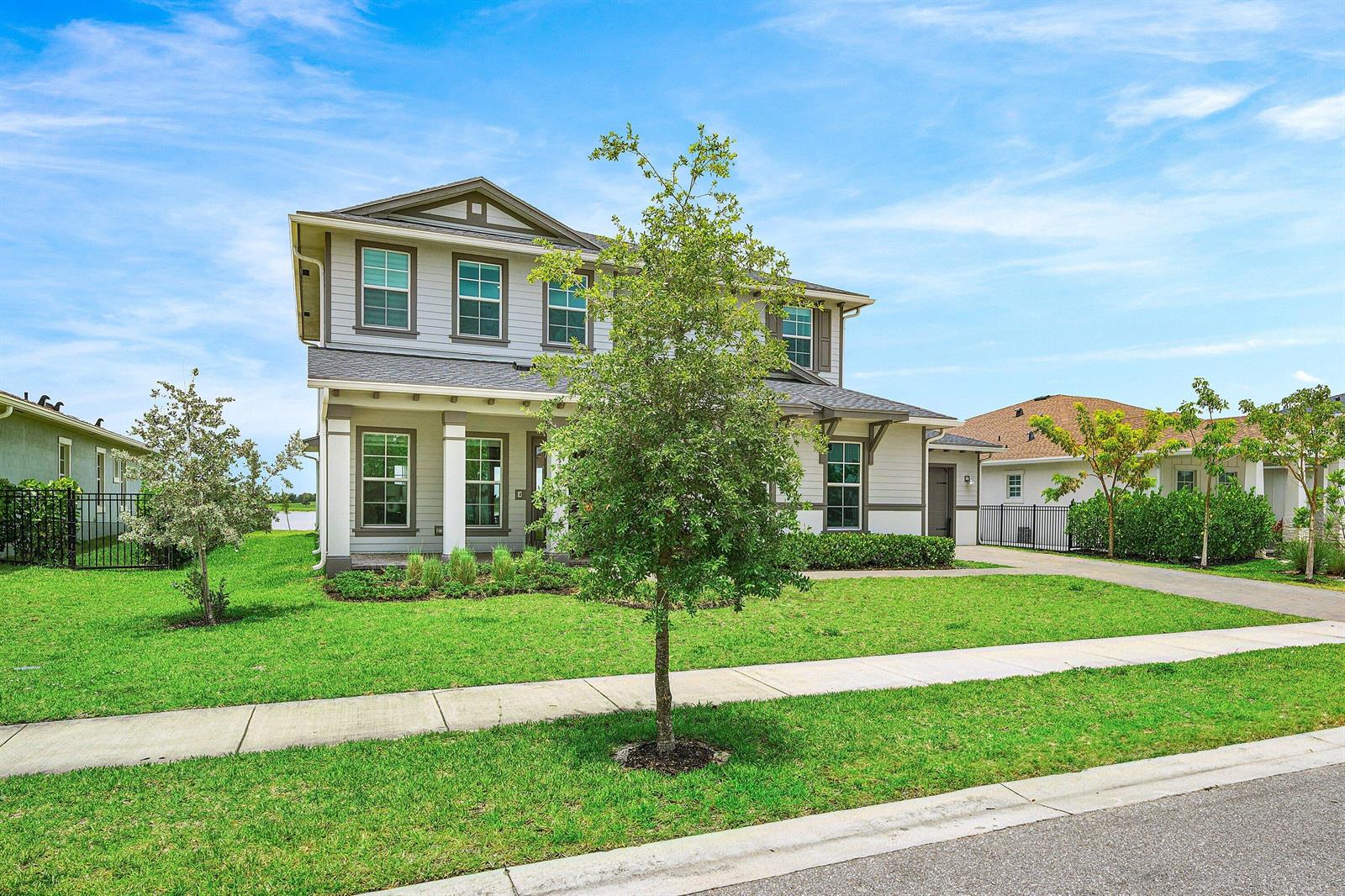 A two-story house with light-colored siding, a front porch, and a green lawn — 655 Hookline Circle, Loxahatchee FL 33470, LOXAHATCHEE, FL
