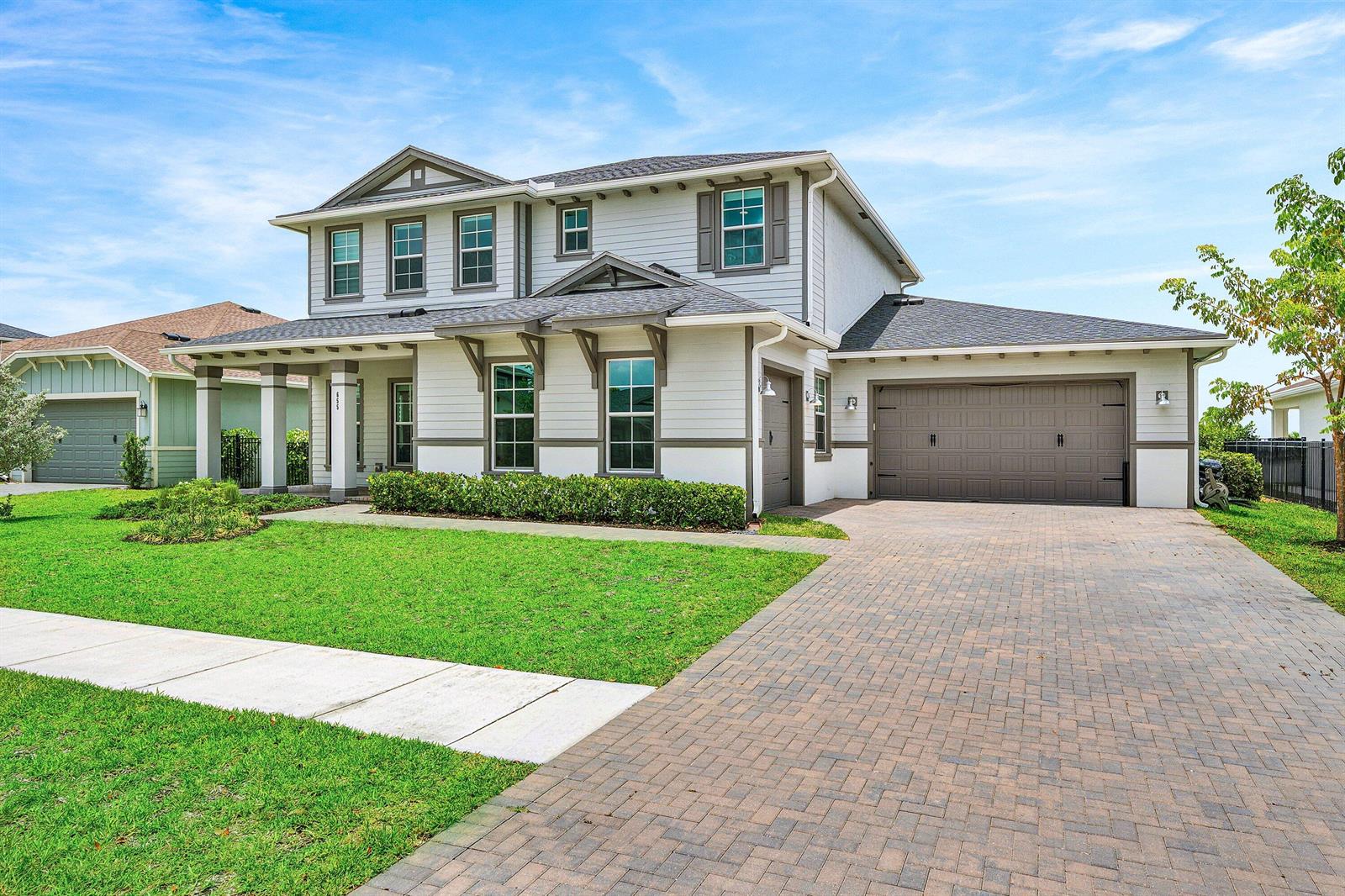 A two-story house with light gray siding, a brick paver driveway, and a two-car garage — 655 Hookline Circle, Loxahatchee FL 33470, LOXAHATCHEE, FL