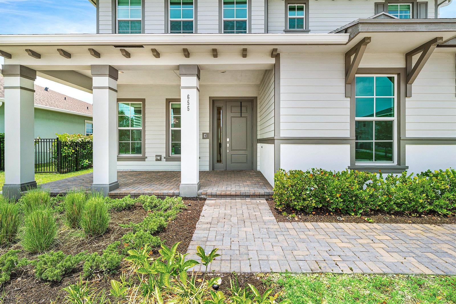 A front exterior view of a house with a covered porch and brick paver walkway — 655 Hookline Circle, Loxahatchee FL 33470, LOXAHATCHEE, FL