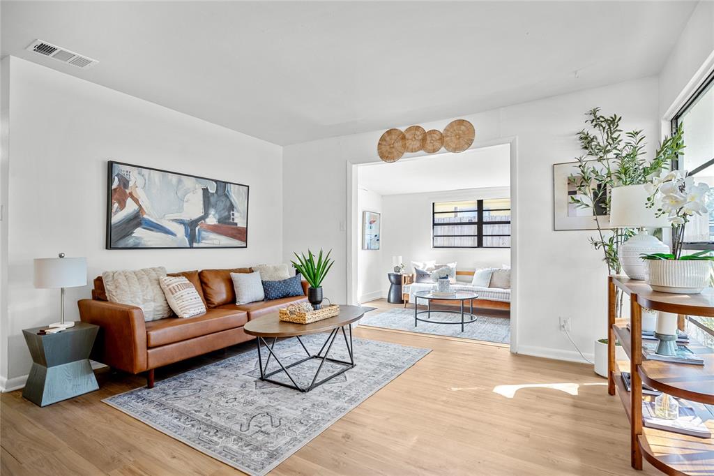 A living room with a leather sofa, area rug, and an opening to a sunroom — 4735 W WISCONSIN AVENUE, TAMPA, FL