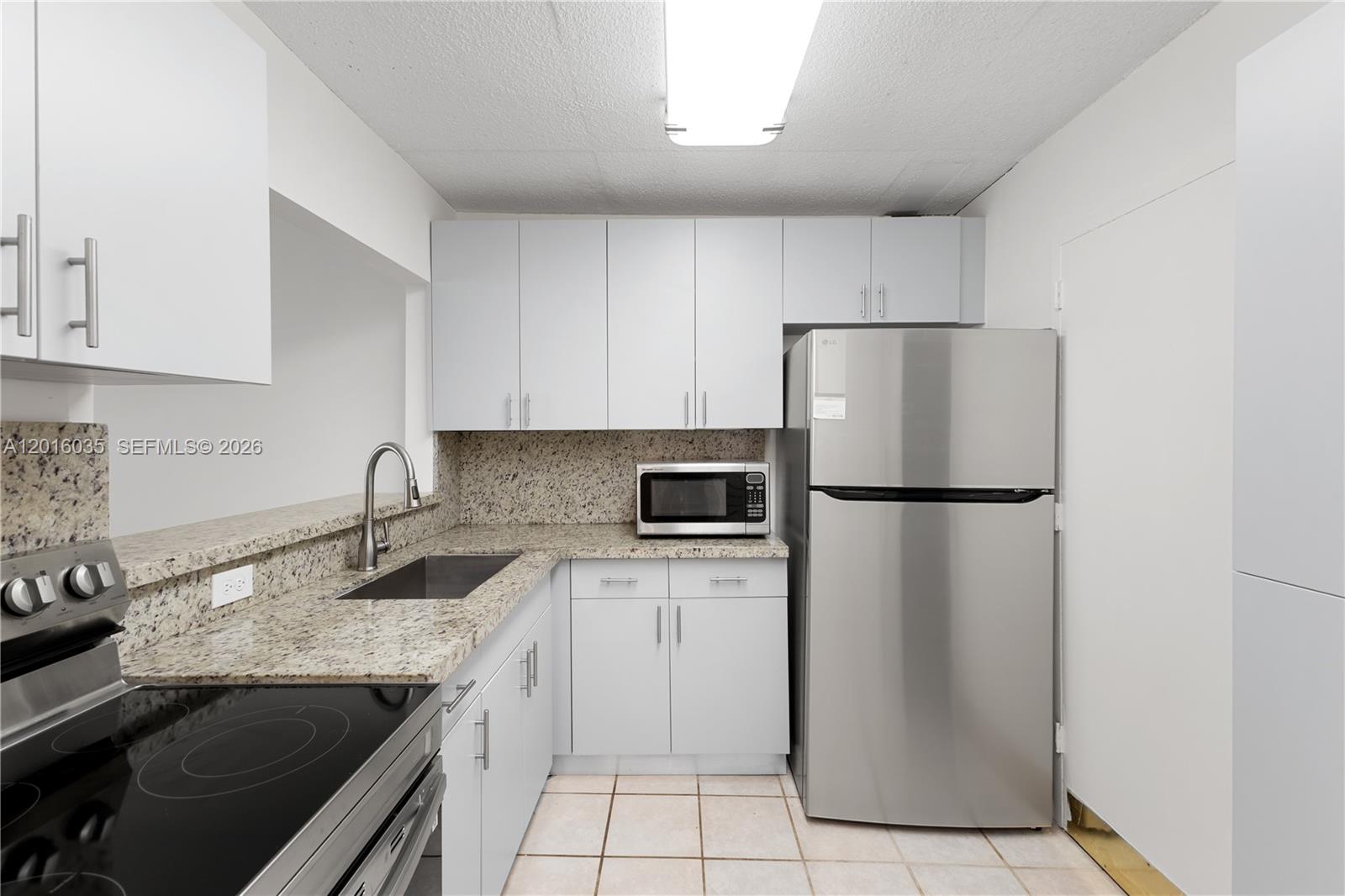 A kitchen features light gray cabinets, granite countertops, stainless steel appliances, and tile flooring — 345 Ocean Dr # 424, Miami Beach FL 33139, MIAMI BEACH, FL