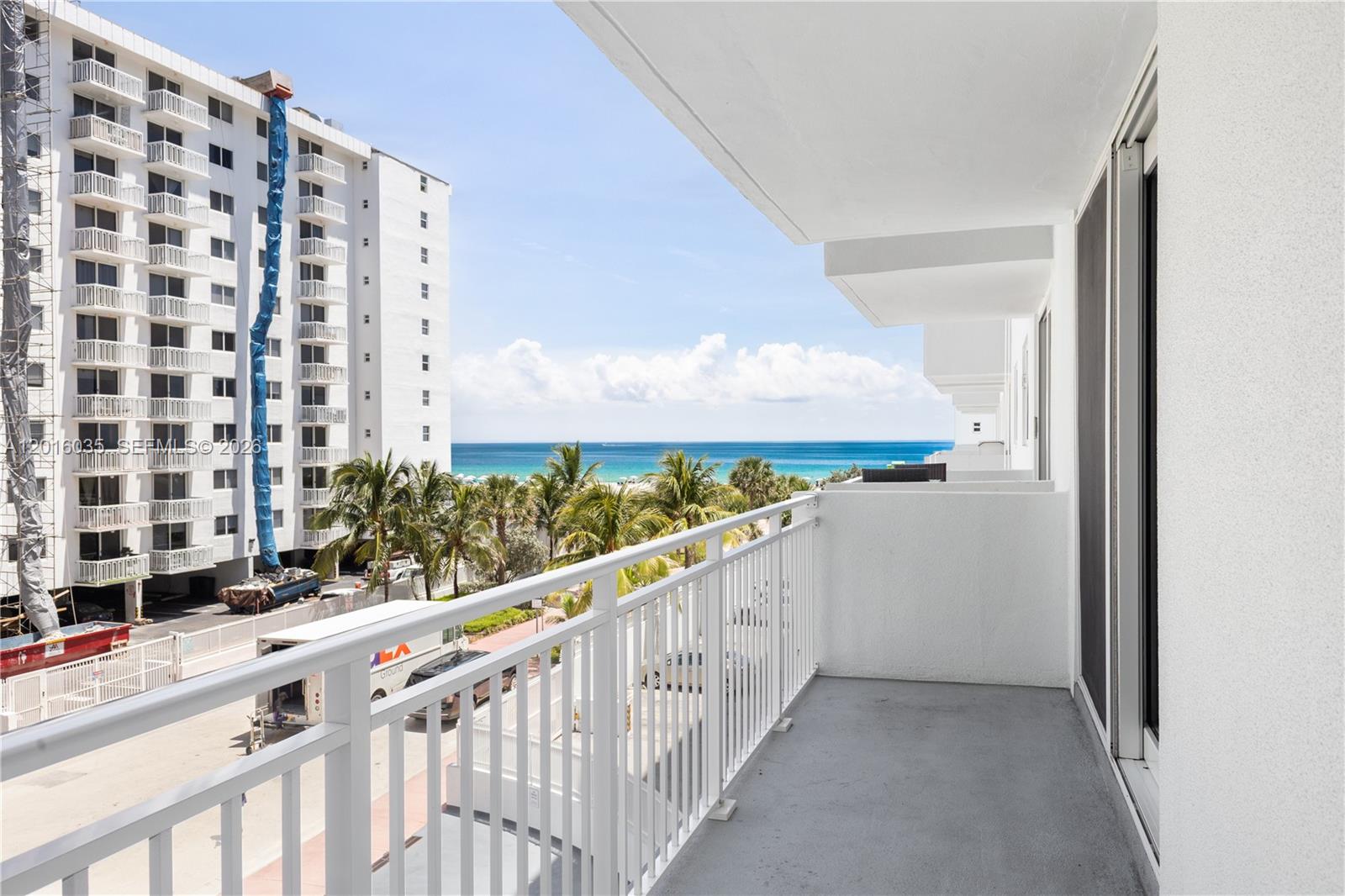 A white balcony with metal railings overlooks a street, palm trees, and the ocean — 345 Ocean Dr # 424, Miami Beach FL 33139, MIAMI BEACH, FL