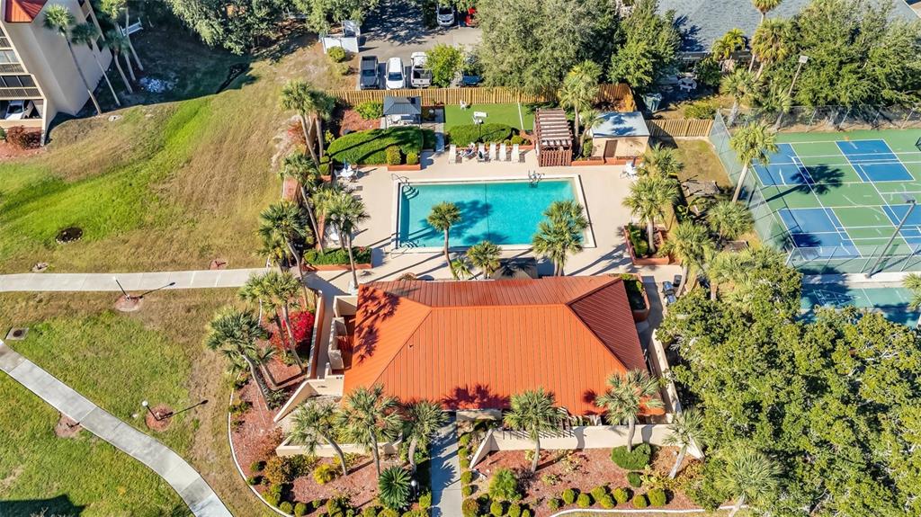 An aerial view shows a swimming pool, a clubhouse with a red roof, and tennis courts — 3006 CARING WAY UNIT 615, PORT CHARLOTTE, FL