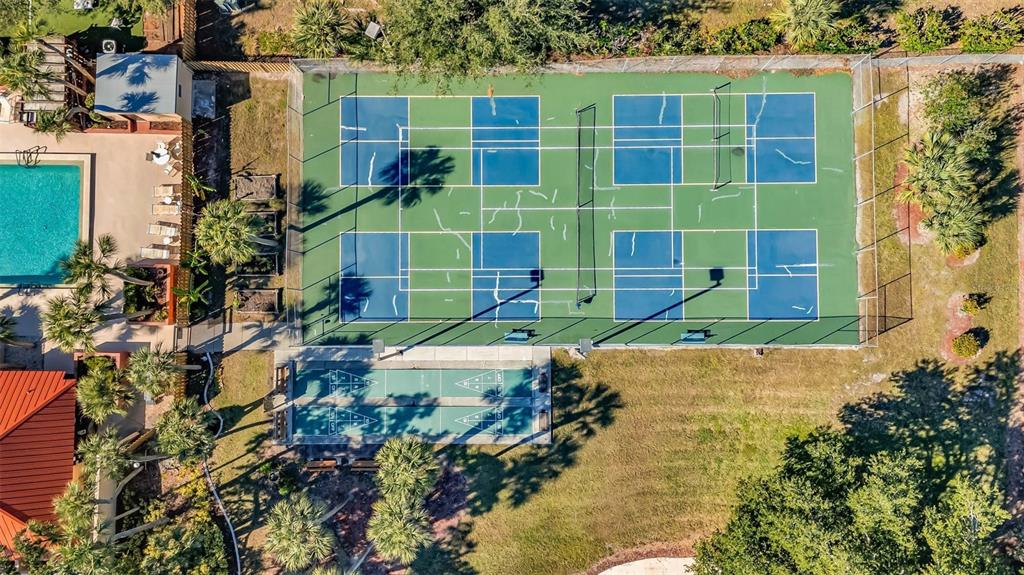 An aerial view shows a fenced pickleball court complex next to a swimming pool area — 3006 CARING WAY UNIT 615, PORT CHARLOTTE, FL