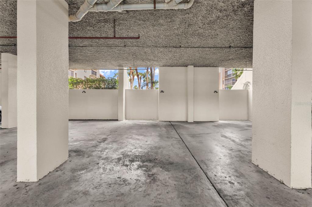 A covered parking garage features concrete pillars, a textured ceiling, and white partition walls — 3006 CARING WAY UNIT 615, PORT CHARLOTTE, FL