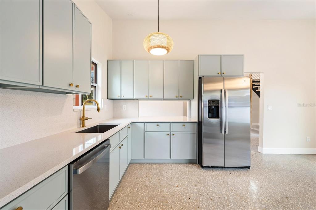 A kitchen features light blue cabinets, stainless steel appliances, gold hardware, and speckled flooring — 419 64TH AVENUE S, ST PETERSBURG, FL